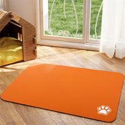 Tapis de repas Nidofé Rive orange, avec motif de patte, posé sur un sol en bois.