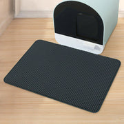 Un tapis alvéolé noir du lot Nidofé Alvéa, placé devant un bac à litière.