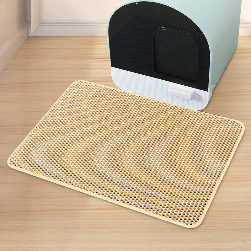 Un tapis alvéolé beige du lot Nidofé Alvéa, placé devant un bac à litière.