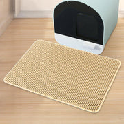 Un tapis alvéolé beige du lot Nidofé Alvéa, placé devant un bac à litière.