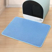 Un tapis alvéolé bleu du lot Nidofé Alvéa, placé devant un bac à litière.
