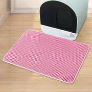 Un tapis alvéolé rose du lot Nidofé Alvéa, placé devant un bac à litière.