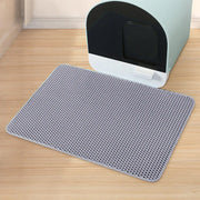 Un tapis alvéolé gris du lot Nidofé Alvéa, placé devant un bac à litière.